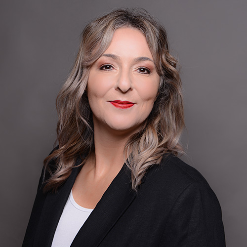 expertum - Eine Frau mit welligen, blonden Haaren und Blazer blickt freundlich in die Kamera-Symbolbild für Fachkräftevermittlung in der Industrie.