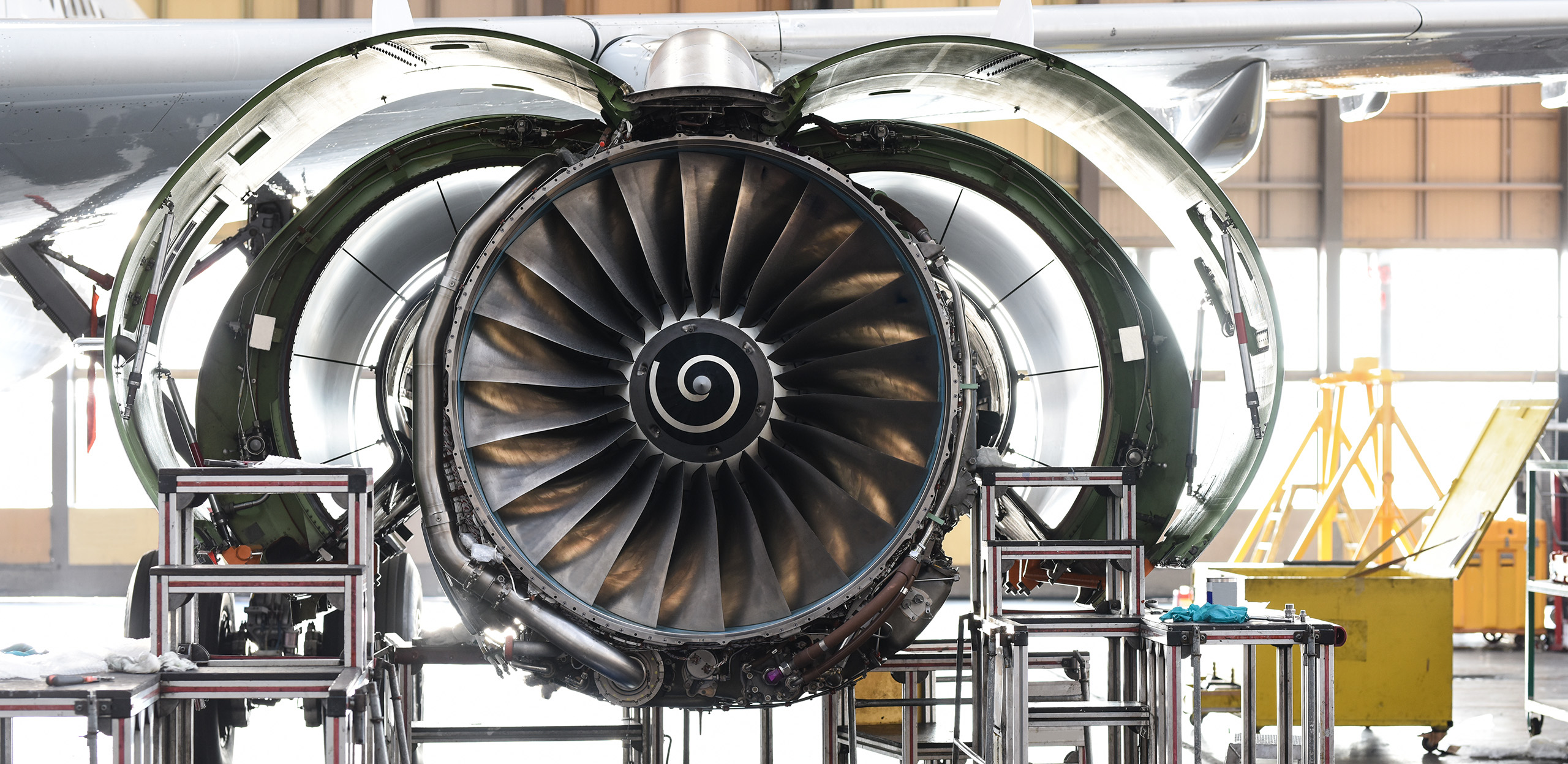 expertum - Nahaufnahme eines Jet-Triebwerks, dessen äußere Verkleidungen für Wartungsarbeiten in einem Hangar geöffnet sind. Zu sehen sind die Turbinenschaufeln sowie verschiedene Werkzeuge und Ausrüstungsgegenstände rund um das Triebwerk. Die Szene verdeutlicht den fachgerechten Einsatz von qualifiziertem Personal und technischem Know-how im industriellen Umfeld – ein Arbeitsalltag, wie er für Fachkräfte in den Bereichen Instandhaltung, Projektarbeit oder Personaldienstleistungen typisch ist und sowohl Bewerbern als auch Unternehmen Perspektiven und Kooperationsmöglichkeiten aufzeigt.